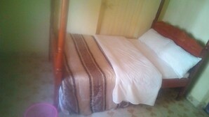 A single bed with a wooden frame and a striped bedspread. - Maleck Guest Rooms (Ruiru)