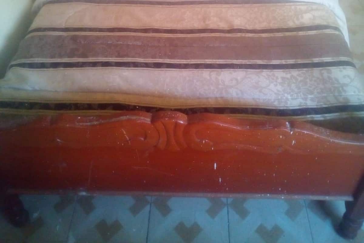 A single bed with a wooden headboard and a patterned mattress.
