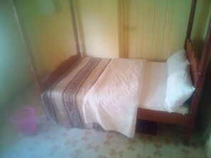 A single bed with a wooden frame and a striped bedspread. - Maleck Guest Rooms (Ruiru)