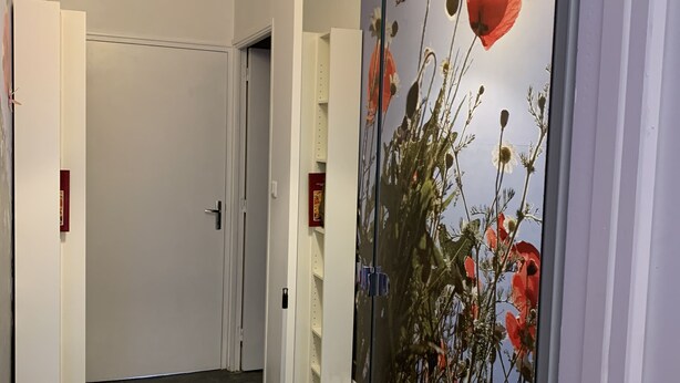 A hallway with a large floral mural, white pendant lights, and a door at the end.