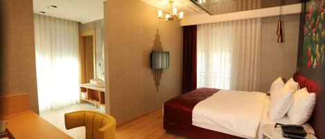 A hotel room with a bed, a desk, a chair, a TV, and a balcony.