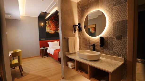 A modern hotel room with a large bed, a round mirror, and a unique patterned wall. - My Garden Hotel (Istanbul)