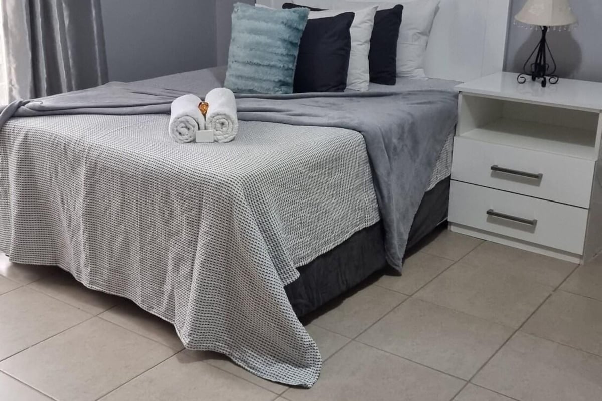 Un dormitorio con una cama, una mesita de noche, una lámpara y un cuadro en la pared.