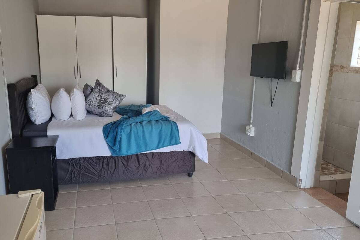 Un dormitorio con cama, mesitas de noche, armario y televisor.