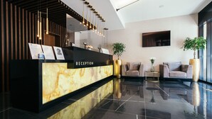 A reception area with a marble counter, modern pendant lighting, and two sofas. - Central Point Hotel (Belgrade)