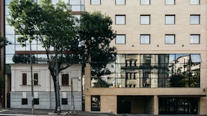 A modern building with a glass facade, a tree in front, and a classical building to the left. - Central Point Hotel (Belgrade)