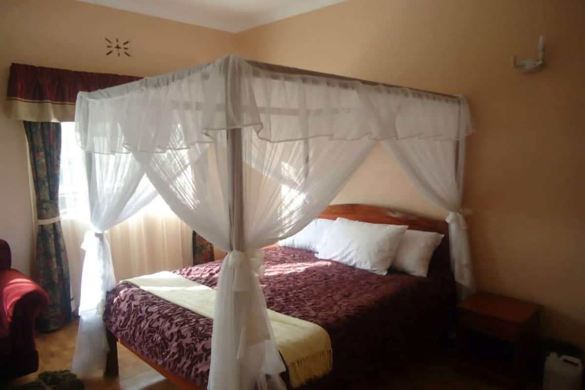 A bedroom with a four-poster bed, a bedside table, and a nightstand.