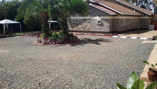 Un edificio de fachada de piedra y techo de tejas, rodeado de grava y una pequeña palmera.