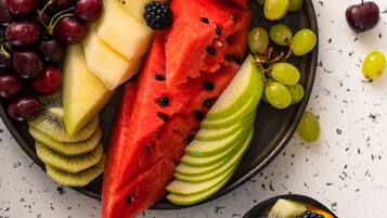 Une assiette de fruits comprenant de la pastèque, des raisins, des kiwis et d’autres fruits.