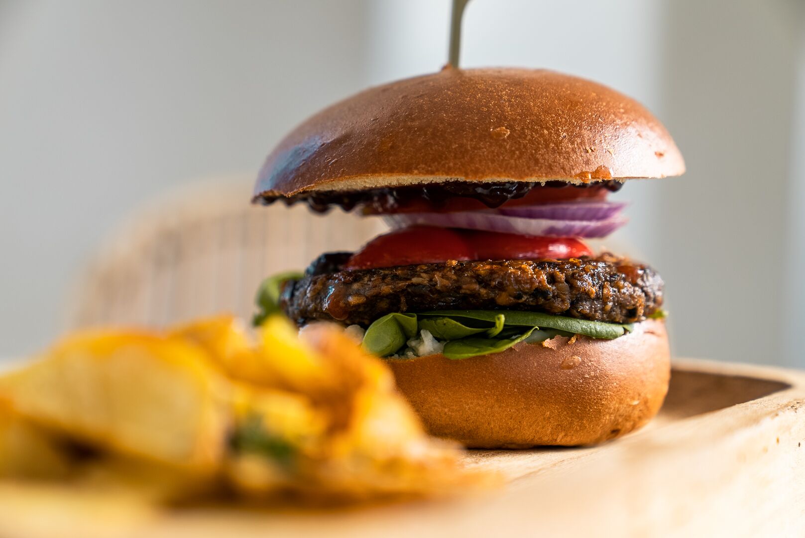 A burger with a bun, lettuce, tomato, and red onion, accompanied by fries.
