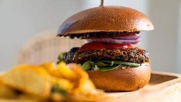 A burger with a bun, lettuce, tomato, and red onion, accompanied by fries.