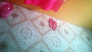 A bathroom with a sink, a patterned floor, and a pink and yellow shower curtain.