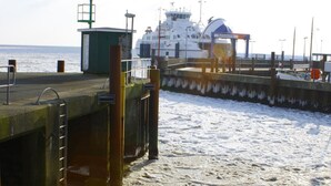 A pier with a ship docked, a small green building, and a concrete wall. - Vacation apartment Kiekin - Kiekut (Wenningstedt-Braderup (Sylt))