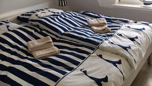 A bed with striped bedding and a window with a view. - Vacation apartment Kiekin - Kiekut (Wenningstedt-Braderup (Sylt))