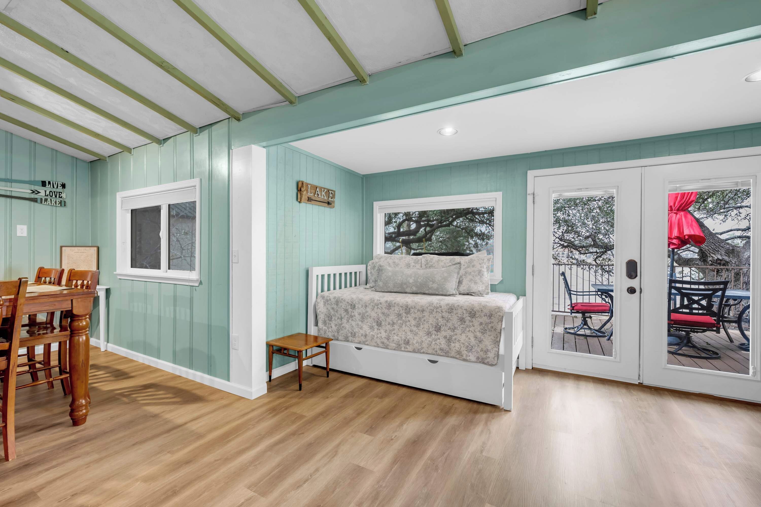 Une chambre à coucher comprenant un lit, une petite table, une fenêtre et une porte donnant sur un espace extérieur.