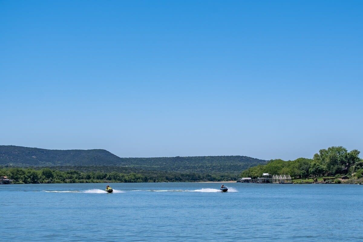 A lake with two boats on the water, surrounded by hills and a clear sky.
