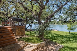 Uma propriedade à beira do lago com uma escadaria de pedra que leva a um deck, cercada por vegetação exuberante e vista para o lago.