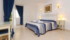A bedroom with a bed, bedside tables, a desk, and curtains.