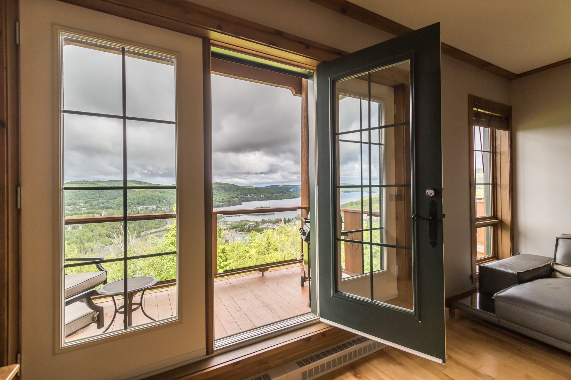 Ein Zimmer mit großen Schiebeglastüren, die auf einen Balkon mit Blick auf einen See und Hügel führen.