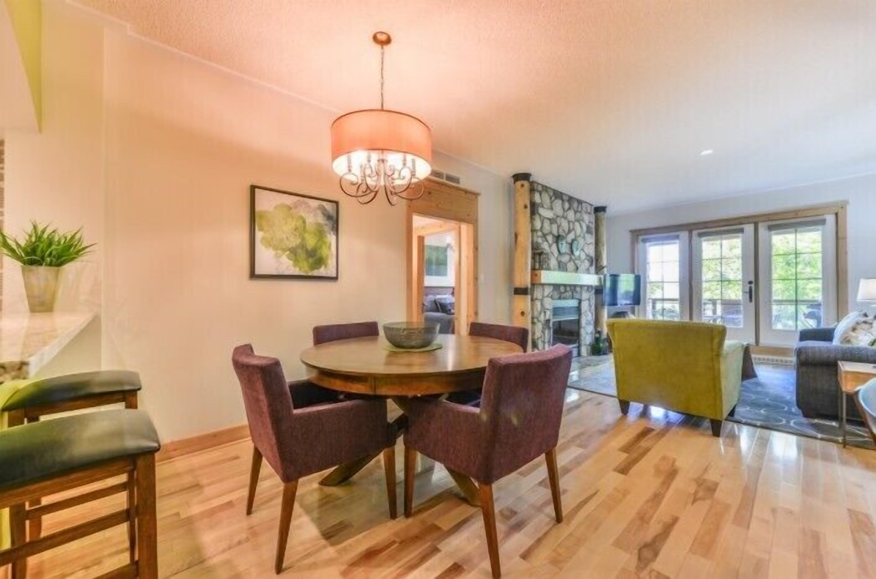 A dining area with a round table, purple chairs, and a chandelier.