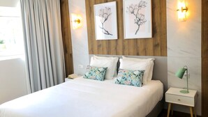Ein ordentlich eingerichtetes Schlafzimmer mit einem Bett, zwei Wandleuchten und einem Nachttisch mit Lampe.