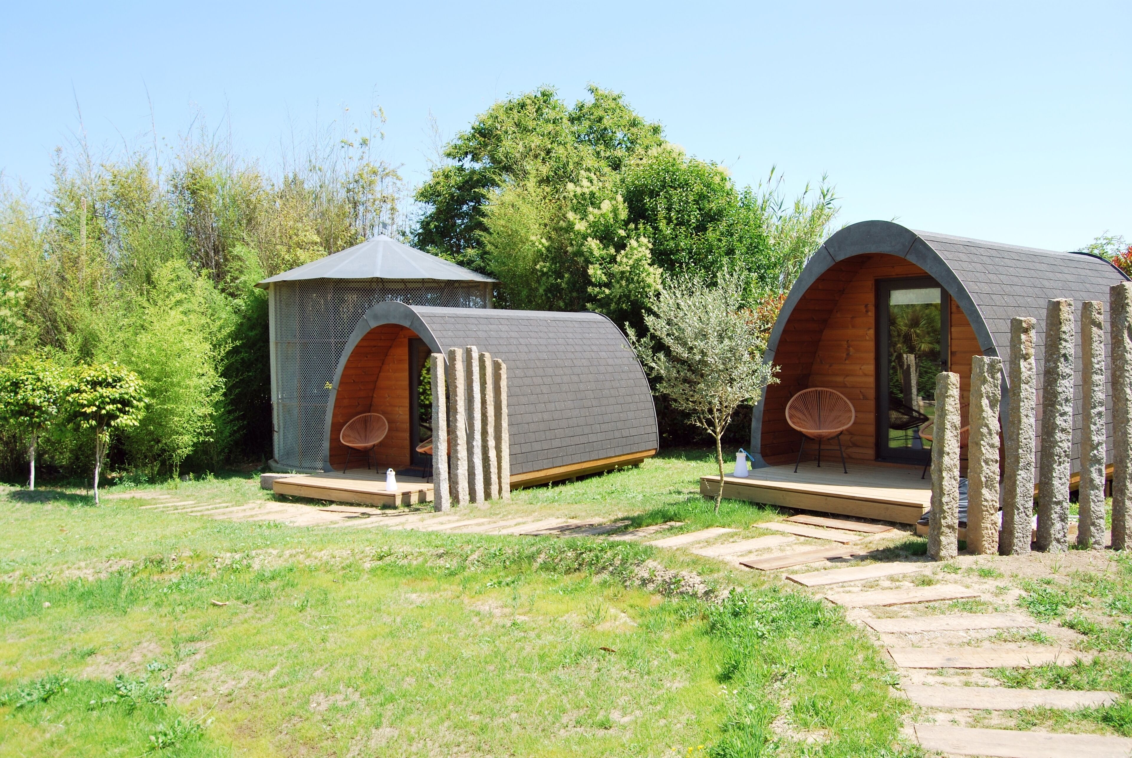Two modern, semi-open wooden cabins with sloped roofs, connected by a wooden deck.