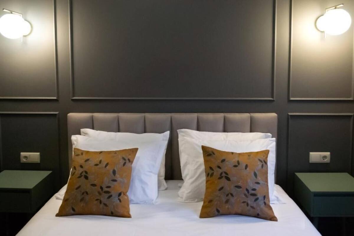 Hotellihuone, jossa on suuri sänky, kaksi yöpöytää ja seinään asennetut valaisimet.