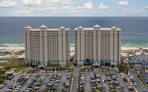 Un hotel de gran altura con varios pisos, un estacionamiento y una playa al fondo.
