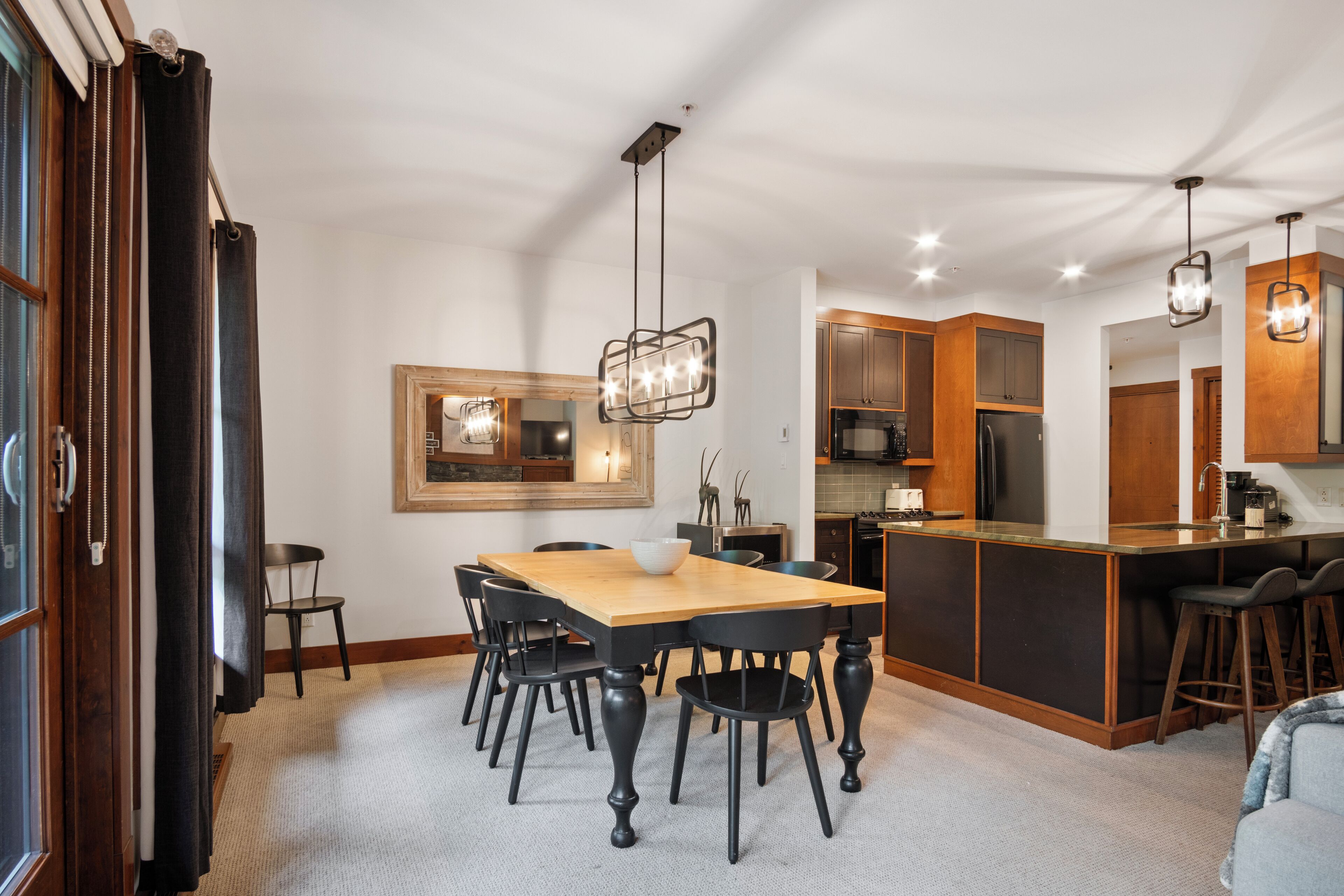A modern kitchen with a central island, wooden cabinets, and a hanging light fixture.