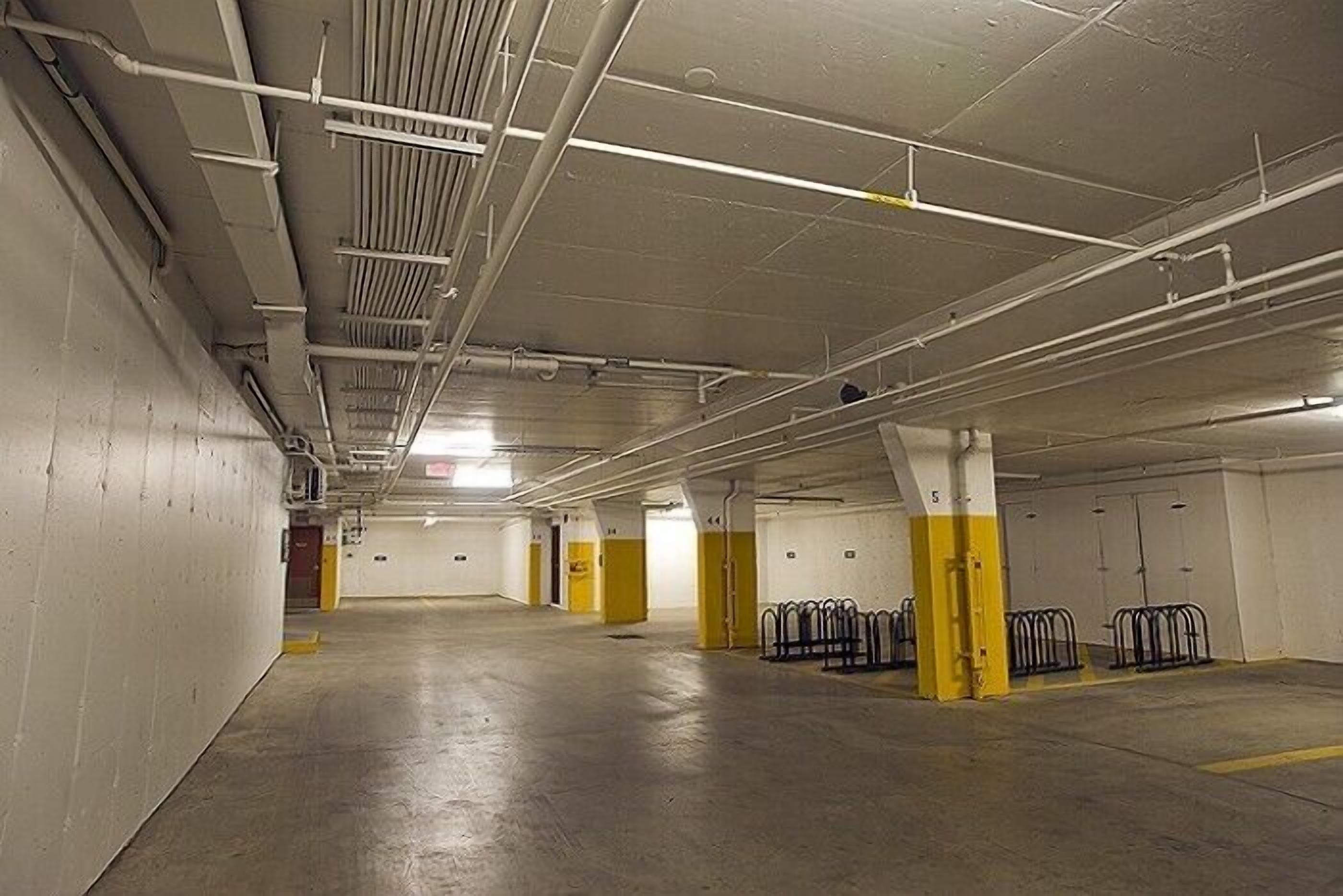 An empty parking garage with concrete floors, white walls, and yellow pillars.
