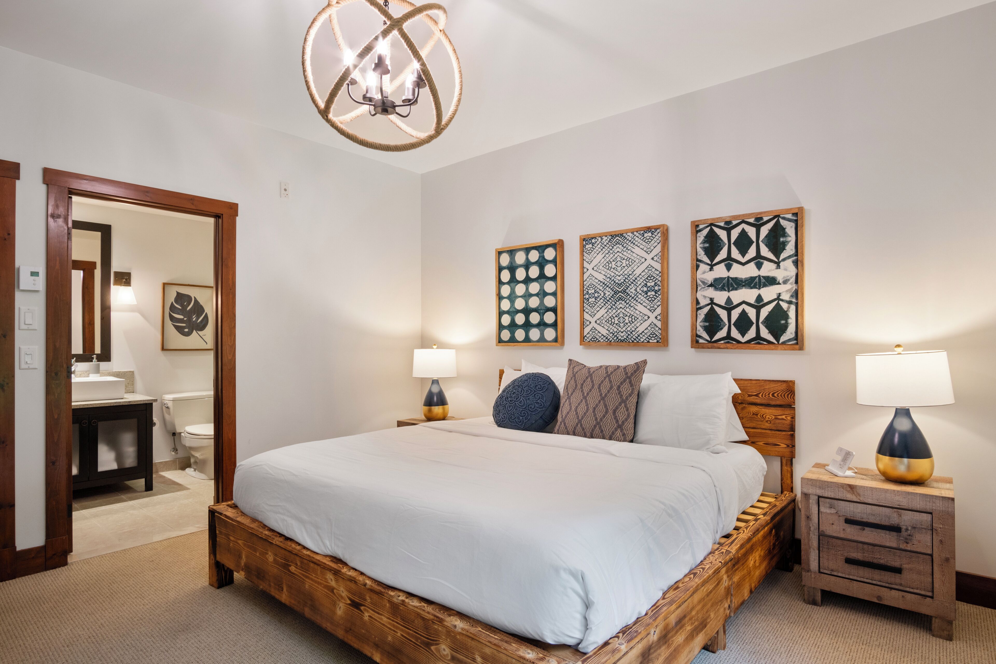A bedroom with a wooden bed, bedside tables with lamps, and wall art.
