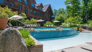 A resort with a swimming pool, lounge chairs, and a large building with multiple balconies.