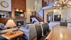 A spacious living area with a fireplace, a wooden staircase, and a modern kitchen.