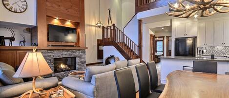 A spacious living area with a fireplace, a wooden staircase, and a modern kitchen.