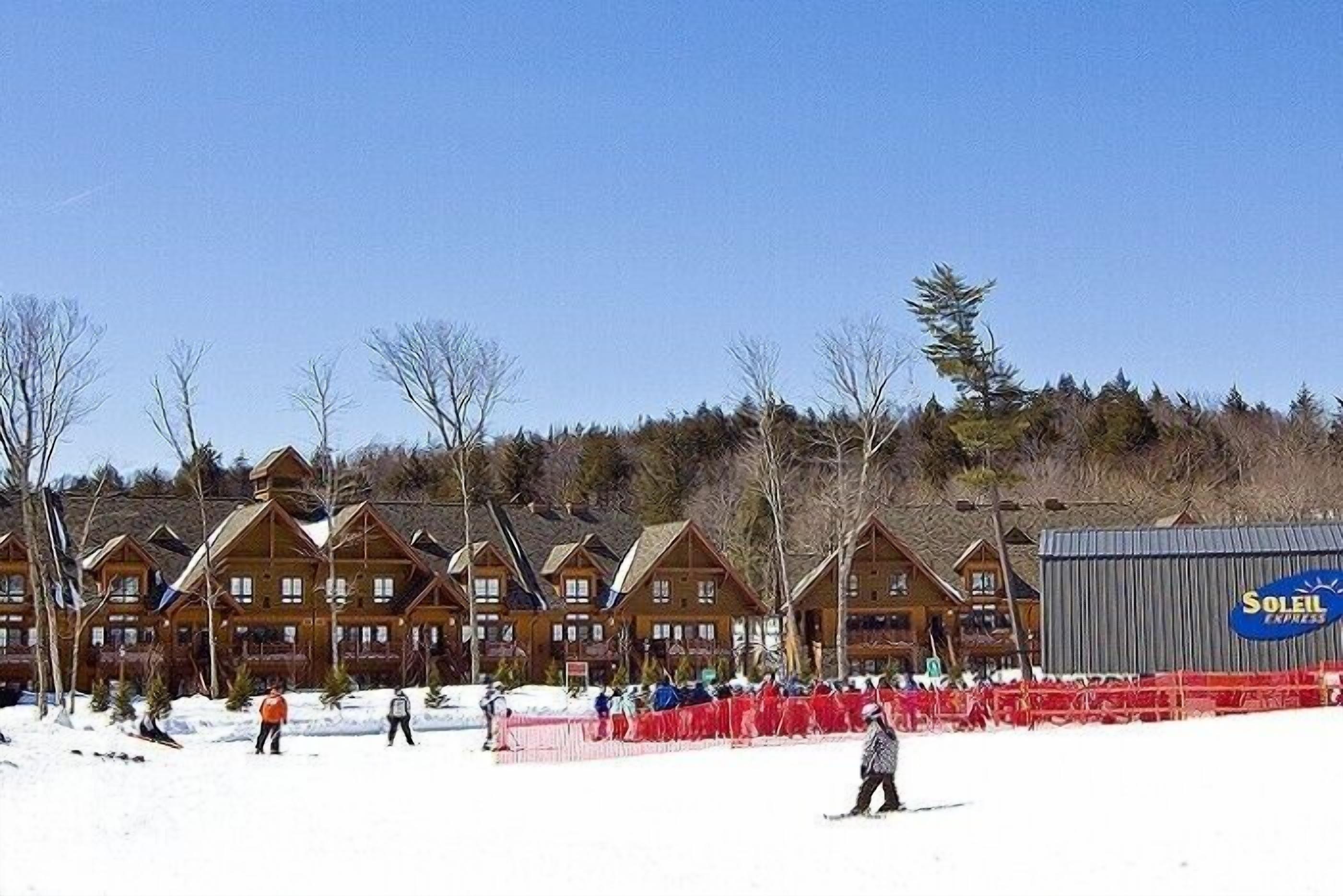 A lodge with multiple wooden cabins, a large building with a 'Soleil Express' sign, and a snow-covered ground.