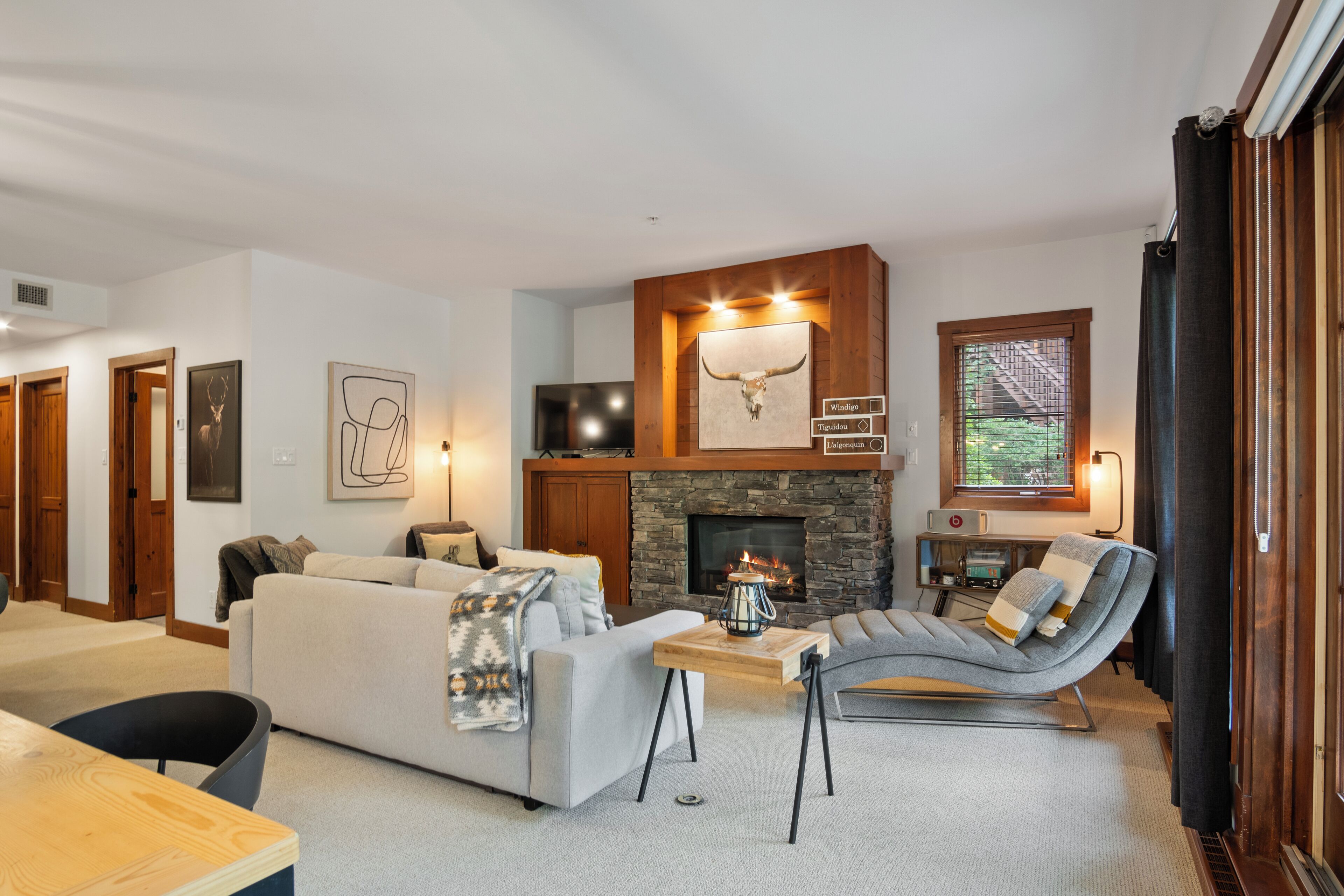 Un salon moderne avec une cheminée en pierre, un crâne d’animal accroché au mur et un coin salon confortable.