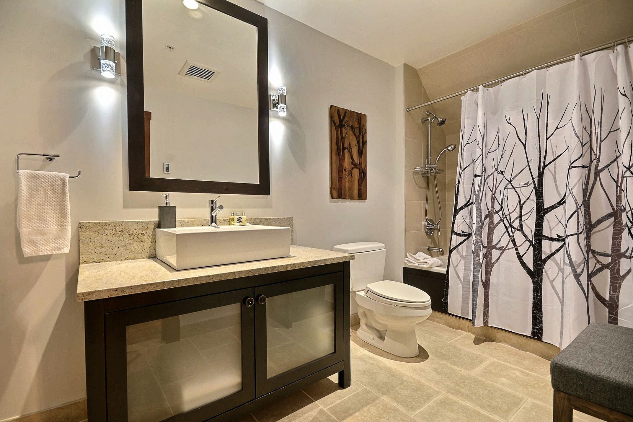 A modern bathroom with a large mirror, a sink, a toilet, and a shower.