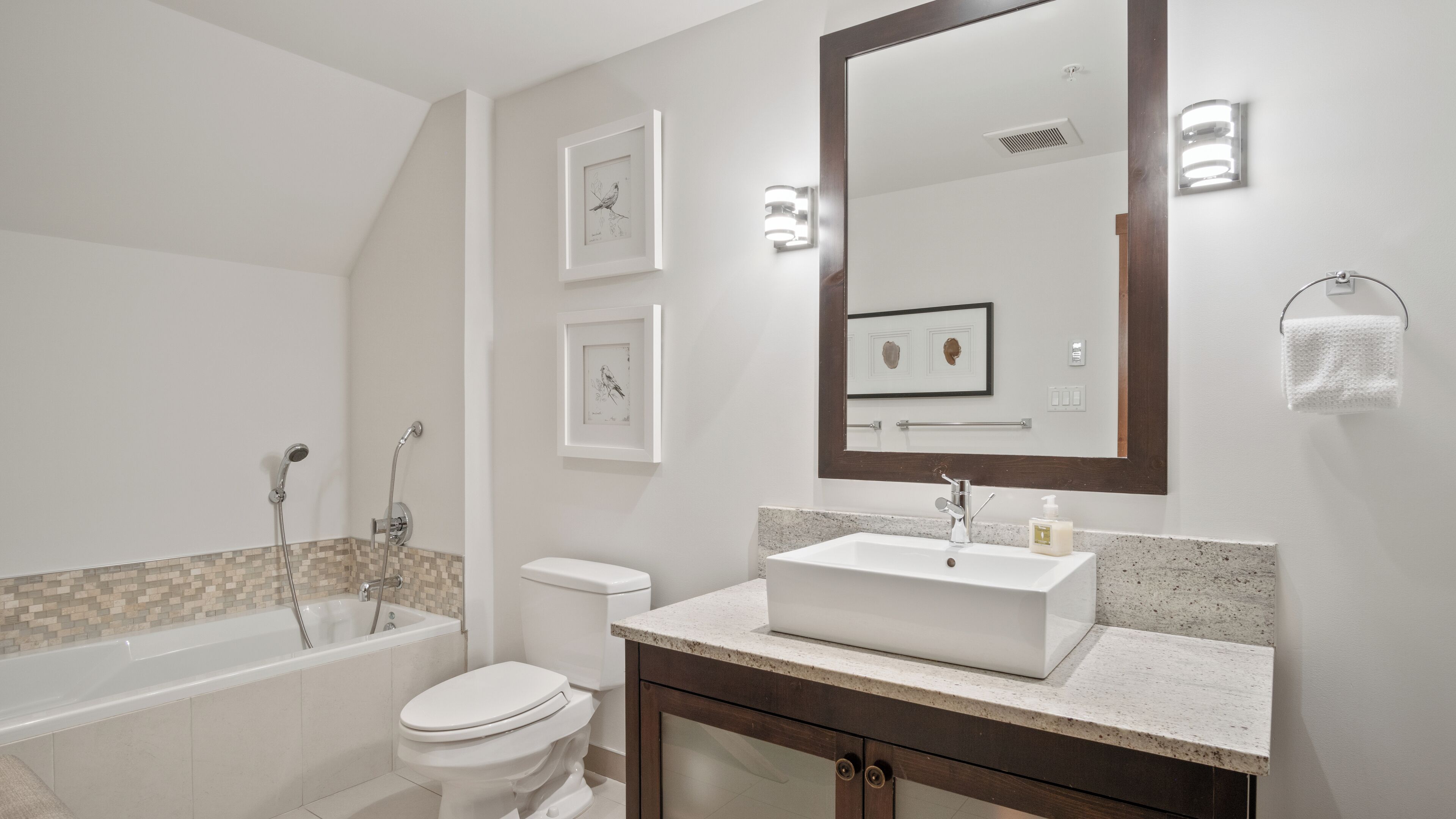 A modern bathroom with a bathtub, toilet, and vanity.
