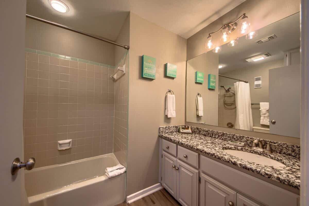 A bathroom with a bathtub, a sink, a large mirror, and a shower area.