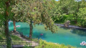 A serene outdoor area with a clear water body, a wooden deck, and a bridge. - CW C107 Spritzen Haus (New Braunfels)