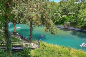 A serene outdoor area with a clear water body, a wooden deck, and a bridge.