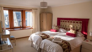 Habitación de hotel con dos camas, un escritorio, un armario y una ventana con cortinas.