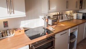 Una cocina moderna con armarios blancos, electrodomésticos de acero inoxidable y encimera de madera.