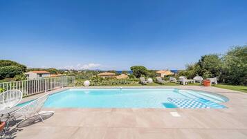 Relax by the serene pool surrounded by lush greenery and comfortable lounge seating.