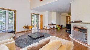 A spacious living room with a fireplace, a dining area, and a large window. - Villa 97 with private pool by Trip2Portugal (Alcácer do Sal)