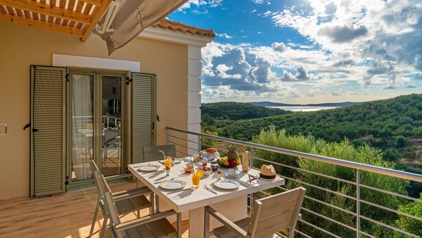 A balcony with a table set for breakfast, overlooking a scenic landscape.