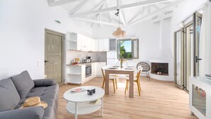 A modern living room with a grey sofa, a round coffee table, and a dining area with a wooden table and chairs.