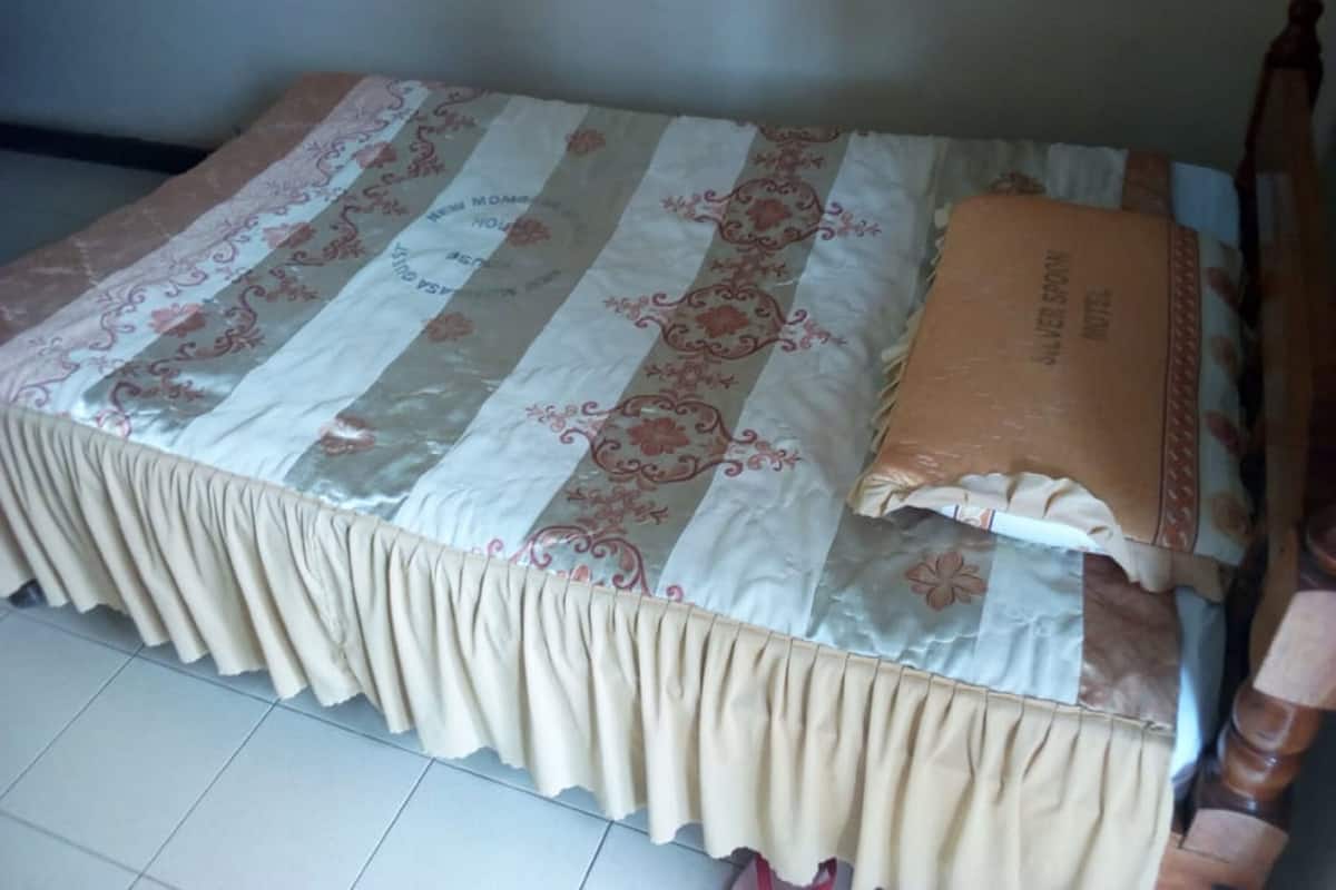 A bed with a striped bedspread and a decorative pillow.