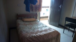 A bedroom with a bed, a chair, and a window. - Mombasa Guest House (Kerugoya)