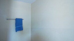 A bathroom with a single blue towel hanging on a metal towel rack. - Mombasa Guest House (Kerugoya)